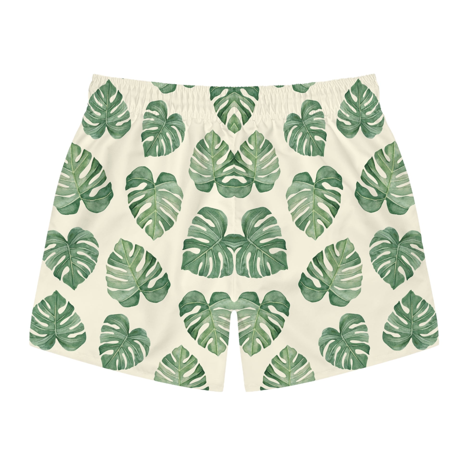 A pair of men's swimming trunks  featuring an all-over green monstera leaf pattern on a warm cream background, displayed flat against a solid white background.